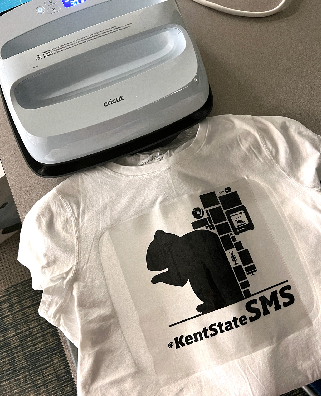 a freshly-pressed tshirt with a Kent State SMS squirrel graphic sits cooling in front of the Cricut EasyPress in the SMS