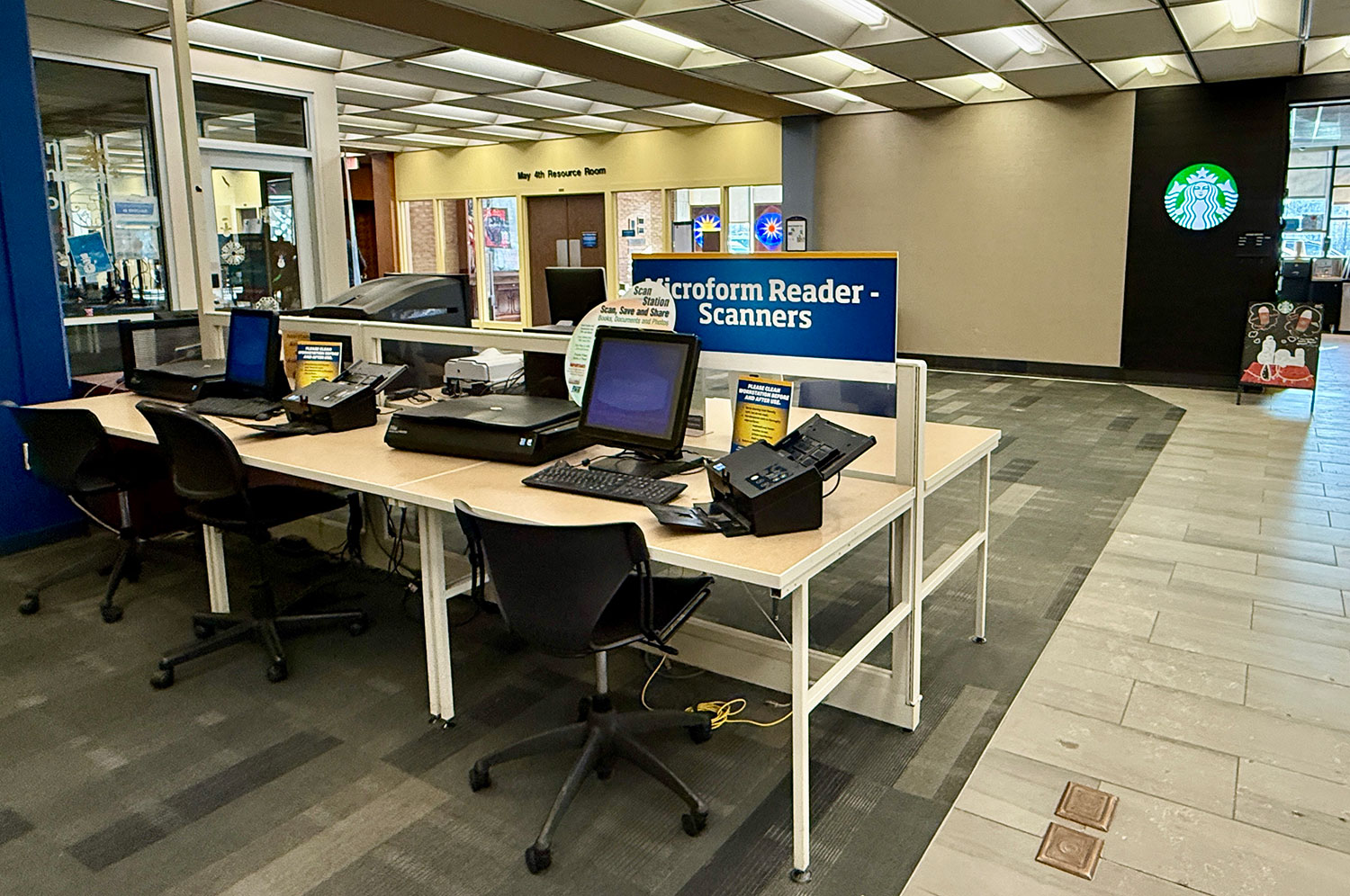 Photograph of 2 scanning stations located on the first floor of the University Library adjacent to the Student Multimedia Studio and Starbucks. Photo includes visual of flatbed and document scanners as well as touchscreen monitor for operating equipment.