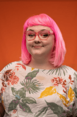 White woman with pink hair and pink glasses