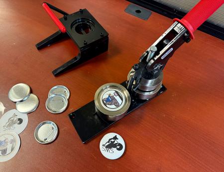 A workstation in the SMS with a button maker, supplies and a punch cutter