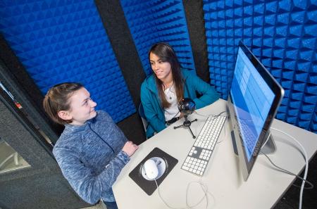 Students record a podcast in the audio recording booth for a course assignment