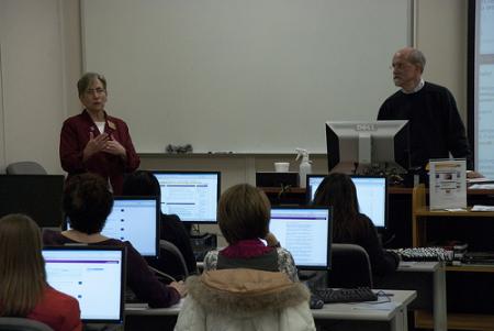 Two lecturers in front of students sitting at computers